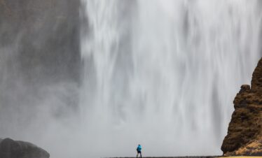 Skogafoss waterfall, man standing in front of a huge wall of water