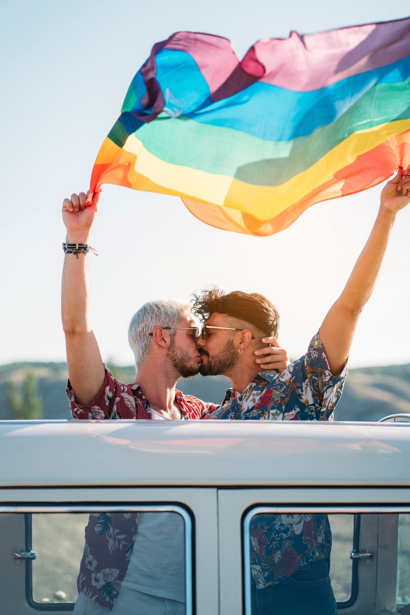 Kissing gay couple holding LGBT flag