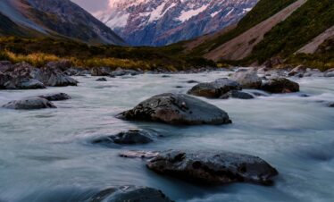 Sunset sky over Mount Cook with the moon and stream flowing in Hooker Valley Track at New Zealand