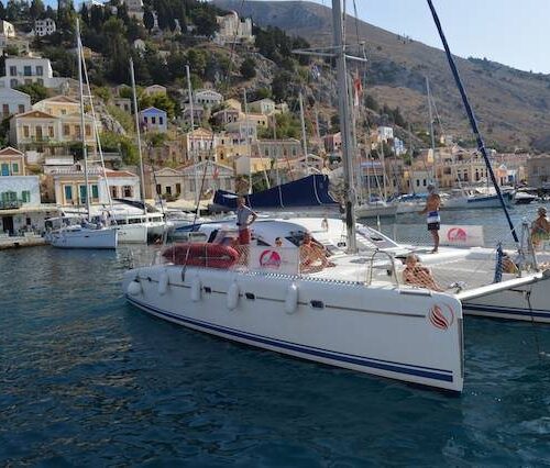 Catamaran moored in the colorful harbor of Symi, Greece