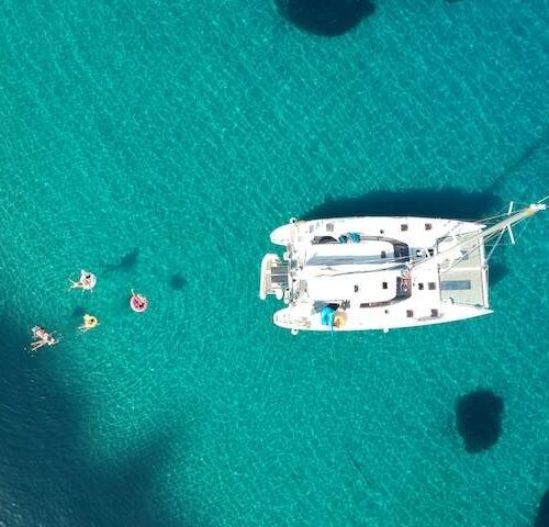Private catamaran anchored in clear blue water among the Greek islands