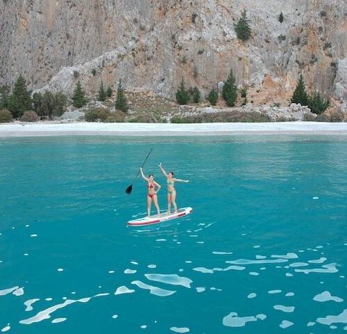 Traveler paddleboarding in a secluded blue bay among the Greek islands